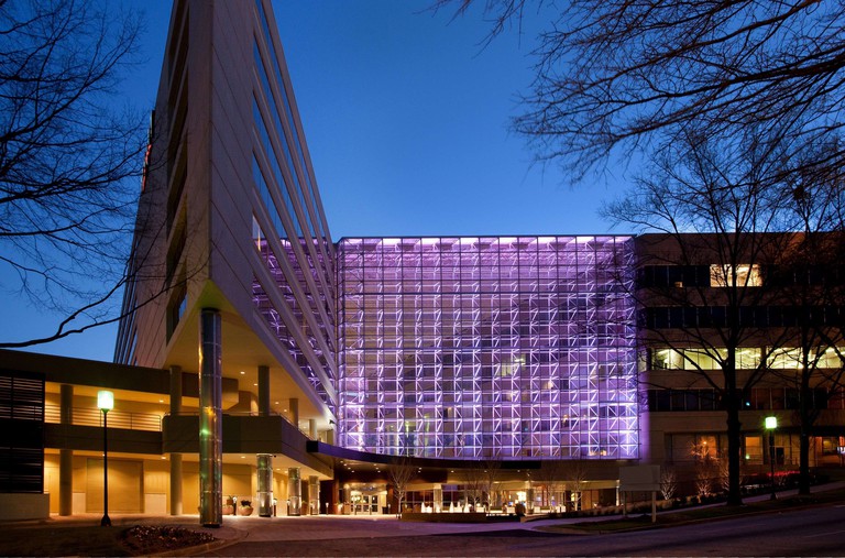 The glassy exterior of Hyatt Regency Greenville, lit up in purple hues at night