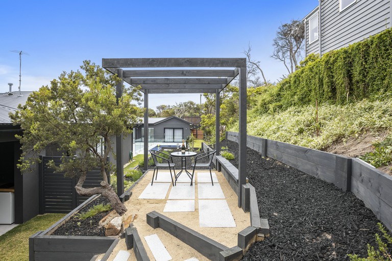 Outdoor raised patio area with pergola and table and chairs at Ocean Sounds Studio