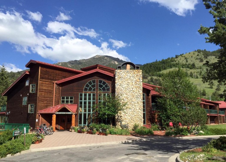 The wood-clad Rock Creek Resort, with stone accents, lots of windows, lush landscaping and mountains in the background