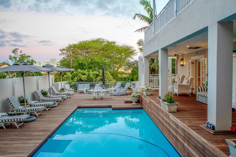 The outdoor pool at Sandals Guest House, surrounded by wooden decking and loungers