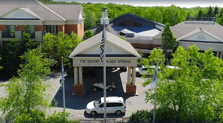 An aerial view of the entrance of the Resort at Glade Springs with a white car in front and trees to the side