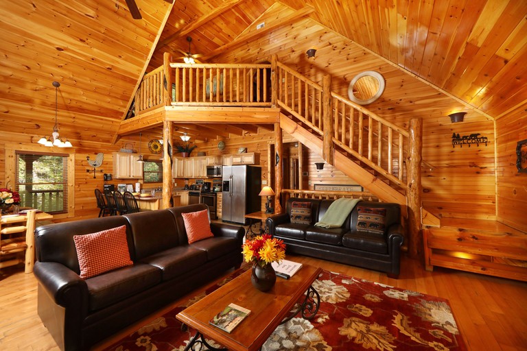 The living area of Smoky Bear Manor, featuring two leather sofas and an open-plan kitchen-dining area
