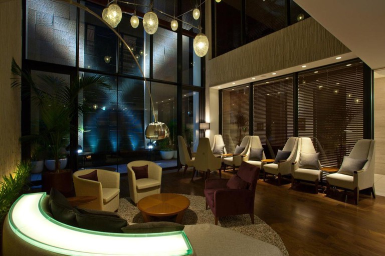A seating area with chairs, a curved couch and hanging lights at Solaria Nishitetsu Hotel Ginza