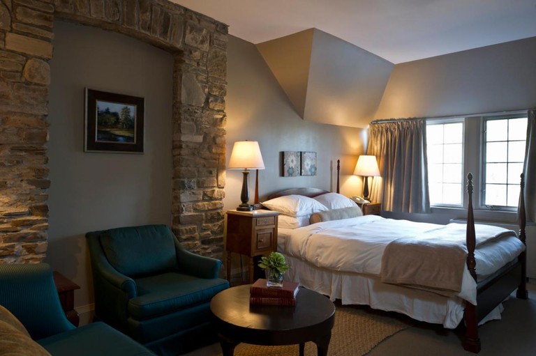 A spacious room with a queen bed, plush seating and a stone accent wall at the Glenerin Inn and Spa