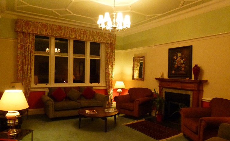 The sitting room at the Beech House Hotel with a fireplace, a sofa and stuffed chairs