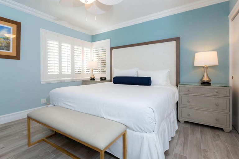 A cozy tranquil queen room with light wood flooring and pale blue walls at Crane's Beach House Boutique Hotel and Luxury Villas