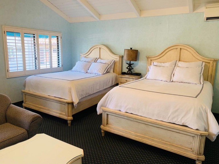 A small but bright room with two double beds at Franciscan Inn & Suites