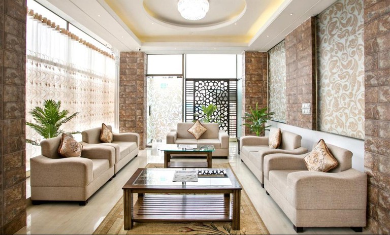 A neutral-coloured sitting area at the White Palace Hotel with oversized chairs, sofas, tables and patterned walls