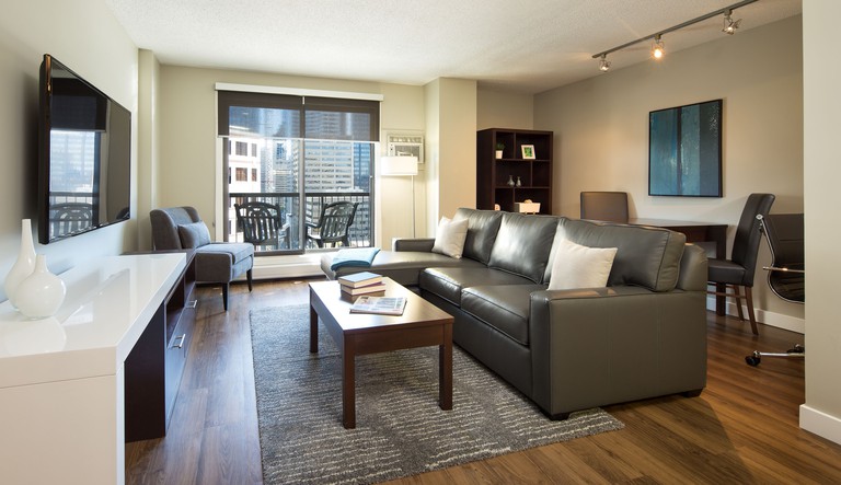 A sleek living space in a room at ExecSuite Calgary with a leather sofa and a flat-screen TV