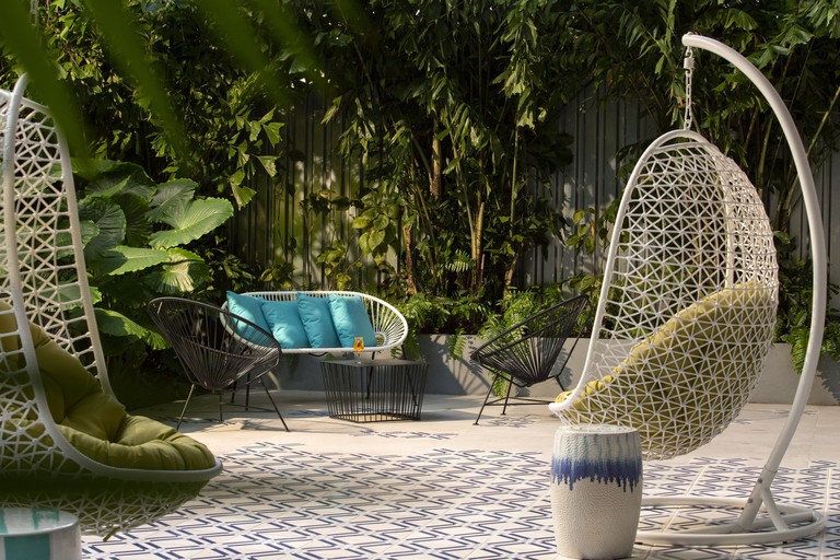 Hanging egg chairs surrounded by plants at Hotel Indigo Miami Brickell