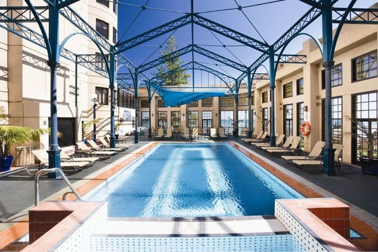 Outdoor pool area enclosed by windows offering ocean view at Stamford Grand Adelaide