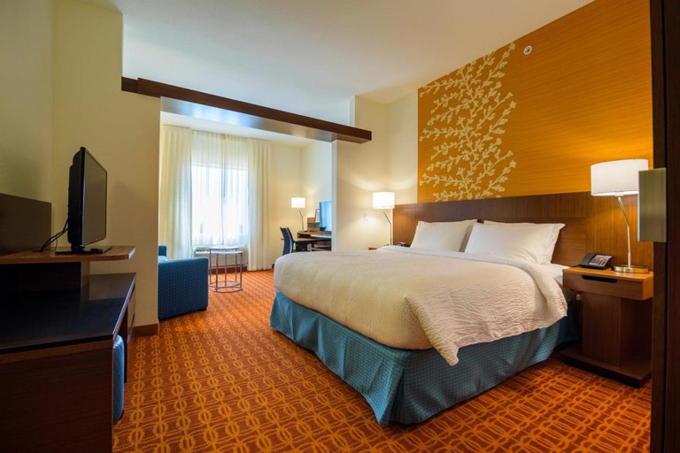King suite with separate seating area in warm rust and yellow hues at Fairfield Inn and Suites by Marriott Delray Beach I-95