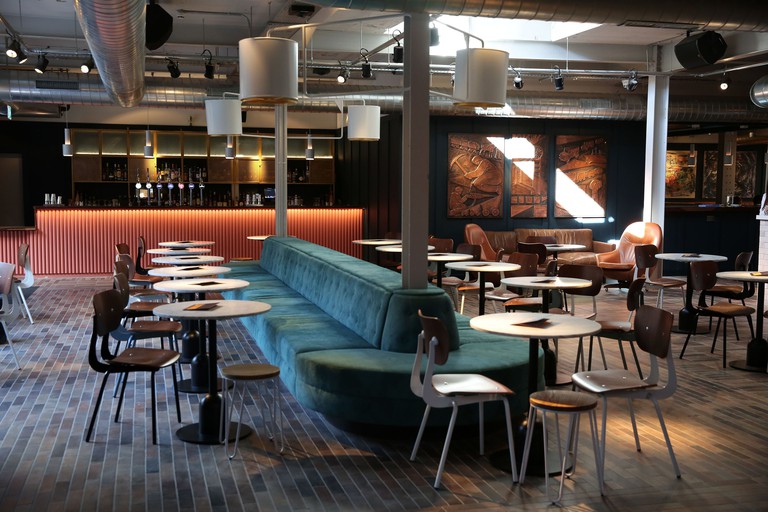 Industrial style bar room at Bullitt Hotel with blue suede sofa and pink bar
