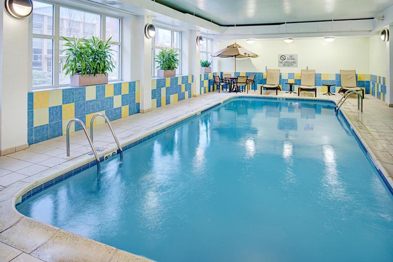 The indoor swimming pool at Hilton Providence, with multi-coloured tiles on the walls and, at the far end, sun loungers and a dining table