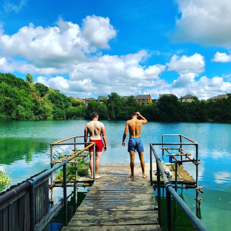 A couple of swimmers survey the water at Divers Cove from a wood platform