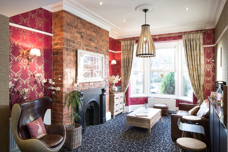 Living room at Hedley House Hotel with red wallpaper, union jack image and dark carpet