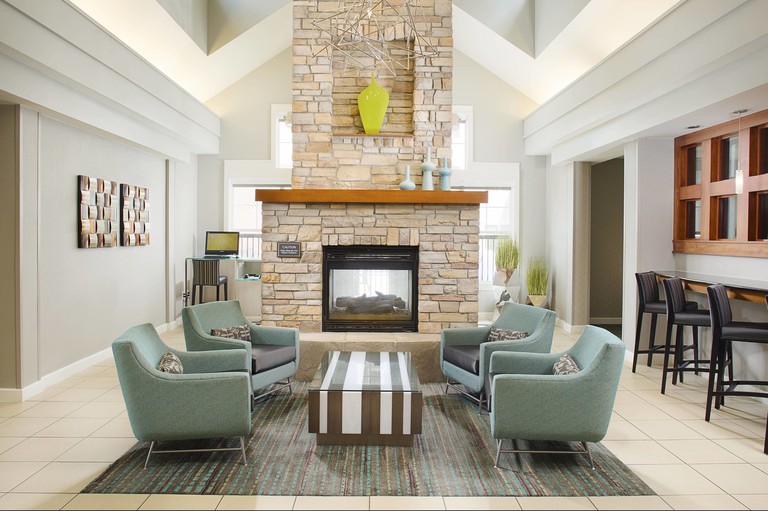 Seating area with fireplace, blue armchairs and geometric wire ceiling lamp shade at Residence Inn by Marriott Roanoke
