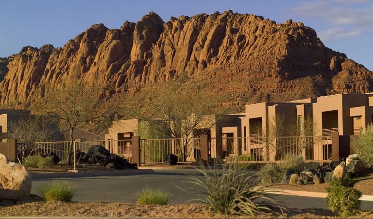 Exterior of lodgings at Red Mountain Resort with mountains behind on a sunny afternoon