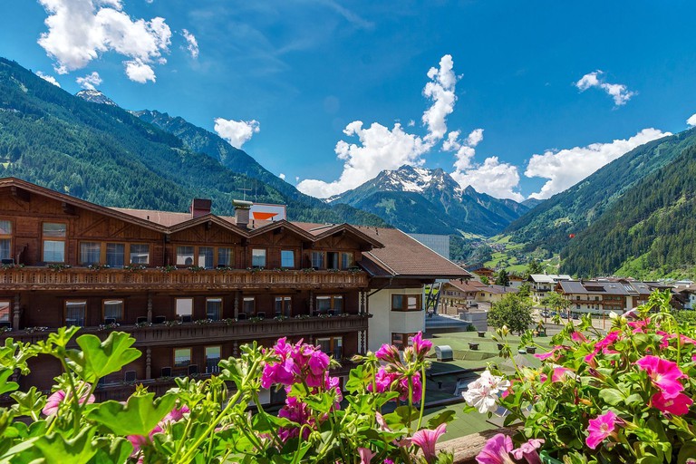 A mid-air view of Sport & Spa Hotel Strass, with grassy mountains all around the area behind