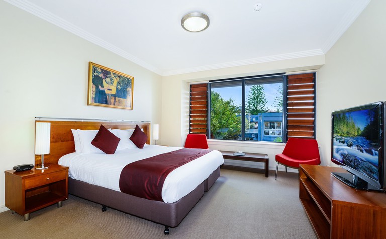 Room at Sebel Harbourside Kiama hotel in Kiama, Australia with red and white decor, a TV and additional seating