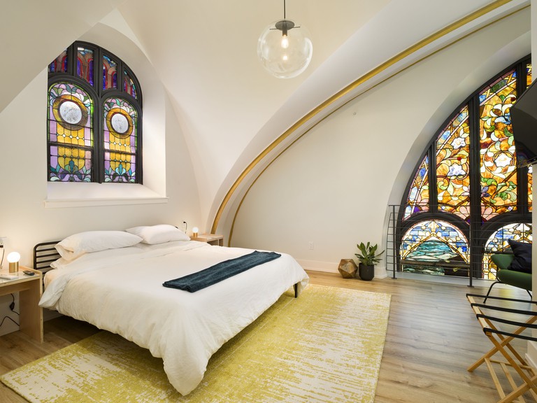 Spacious bedroom with original stained-glass windows and golden arches at the Deacon in Philadelphia
