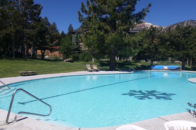 The outdoor pool area at Snowcreek Resort, with a mountain peering through the trees behind