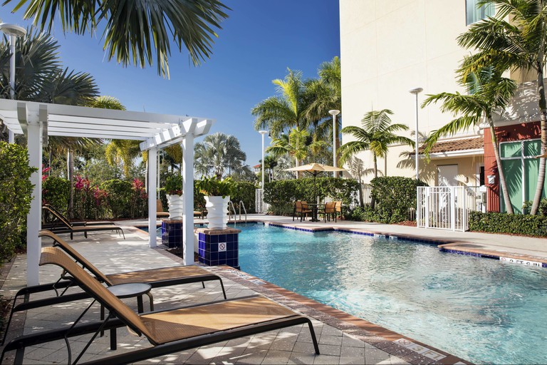 Tropical pool area with lounge chairs at Courtyard by Marriott Miami Homestead