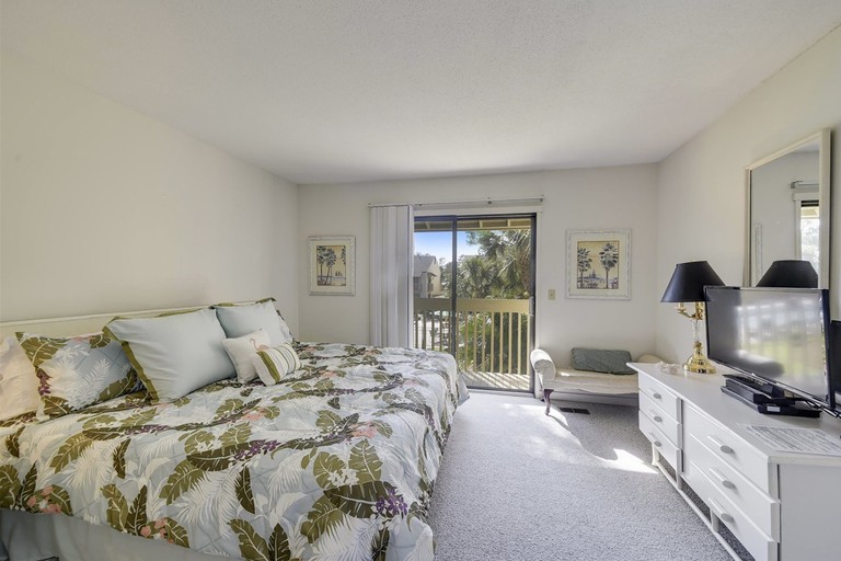 Large king bedroom with palm-print bedspread and white furnishings at Coligny Villas 43 on Hilton Head
