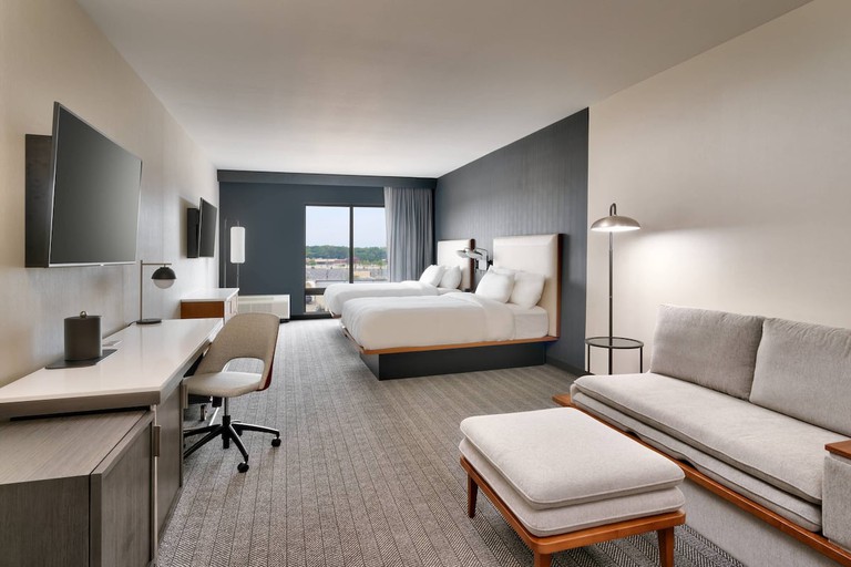 A contemporary room with clean lines at the Courtyard by Marriott Ames featuring two double beds and a sofa