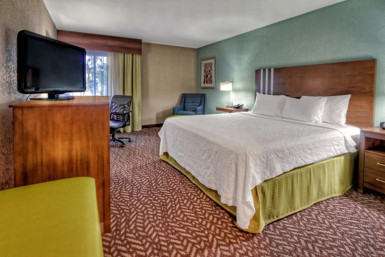 Double room at the the Hampton Inn Beaufort, with retro-style furnishings in brown and mustard yellow, including a wavy geometric rug and a wooden headboard.