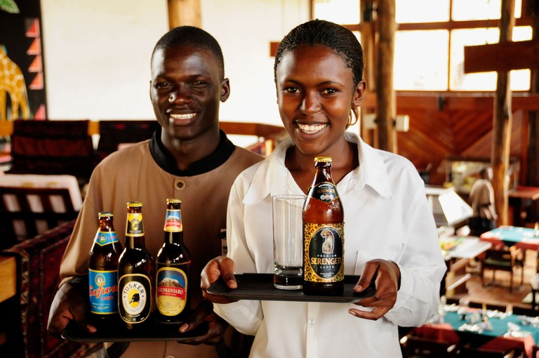 Waiter and waitress carrying the most popular beer brands in Tanzania