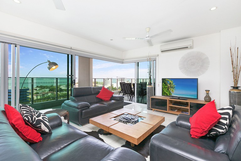 Living room at Beach Life Apartments, Darwin with leather sofas and a balcony overlooking the ocean