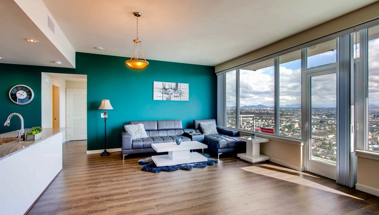 The spacious living room with an attached balcony and city views at the Live in the Ultimate Luxury in San Diego
