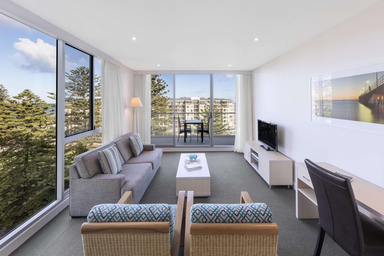 Upscale corner unit living room with floor-to-ceiling windows and balcony at Oaks Glenelg Liberty Suites in Adelaide