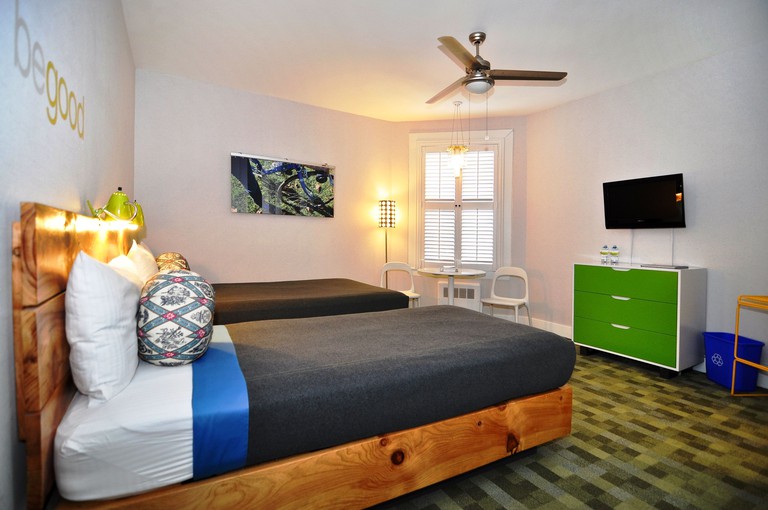 A comfy guest room with two double beds featuring bed frames made out of reclaimed wood at the Good Hotel