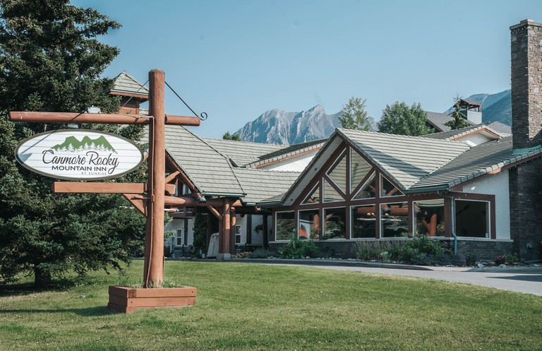 The lodge-style Canmore Rocky Mountain Inn with rocky peaks behind it