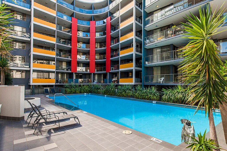 The large pool in the courtyard of the colourful Code Apartment Perth building