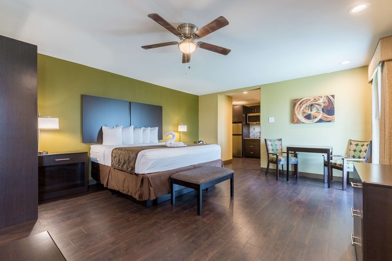 A stylish room at Best Western Padre Island, with a cushioned bed, a dark wooden floor, a table and chairs