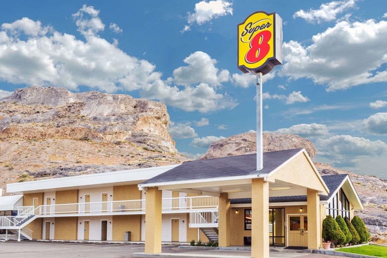 The sand-colored two-story exterior of the Super 8 by Wyndham Wendover, backdropped by rock formations