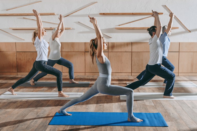 A group in the same yoga pose in a modern studio