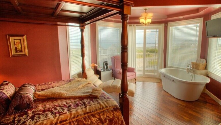Red-walled bedroom at the Collins Inn and Seaside Cottages, with a free-standing bath tub and a four-poster bed