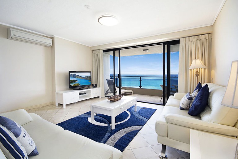 Living room at Clubb Coolum Beach Resort, with white and blue decor and a balcony facing the ocean
