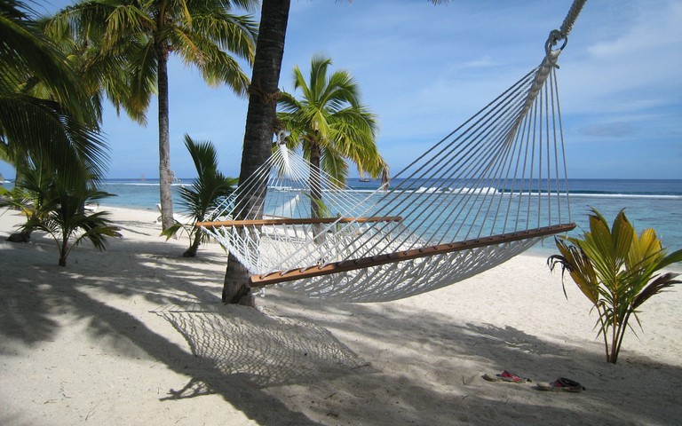 Hammock at Sunset Resort overlooking ocean beneath palms on white sand beach