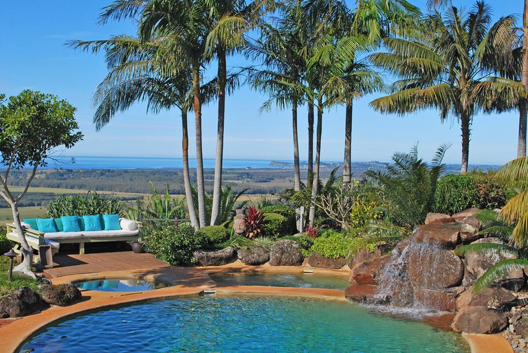 An outdoor pool with a waterfall and sea view at Four Winds Villas Byron Bay