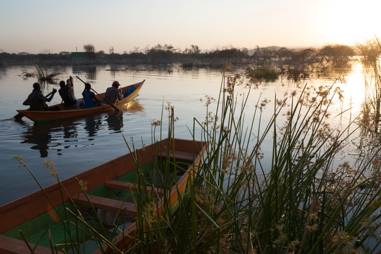 Men row out onto Lake Baringo, in the Rift Valley, on a boat at sunset