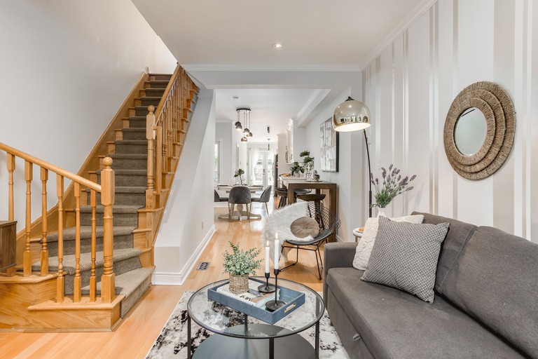 A cozy gray-and-white living room with a staircase on the left at the Homey and Elegant 3-Bedroom Home in the Annex