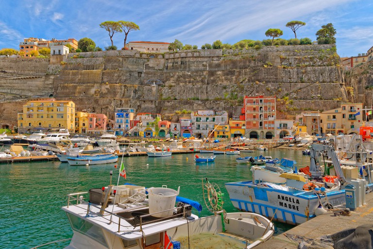 Marina di Cassano in Sant’Agnello, Italy, is surrounded by sheer cliffs and multi-coloured houses, and moored with yachting and fishing boats.