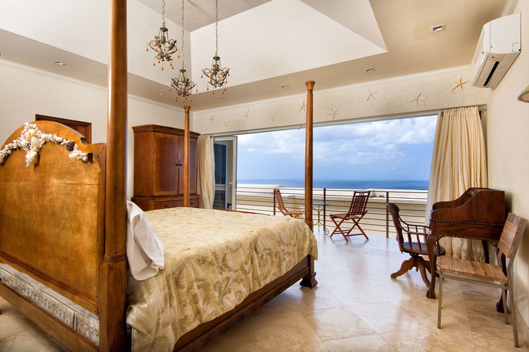 Stately four-poster bed at the LA Maison Michelle, facing an ocean-view balcony
