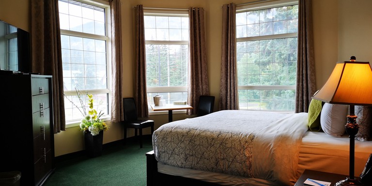 A traditional room at Mountain View Inn with Canadian trees seen through the three windows