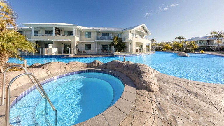 Large outdoor pool, plus a hot tub with steps and handrail, by a two-storey building at Oaks Port Stephens Pacific Blue Resort